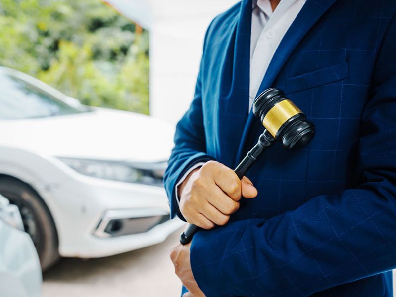 Lawyer holding a gavel with cars in the background, symbolizing DUI legal cases in Norfolk, Virginia. Understanding new DUI laws.