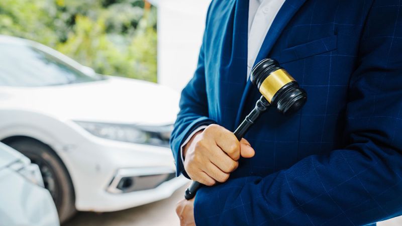 Lawyer holding a gavel with cars in the background, symbolizing DUI legal cases in Norfolk, Virginia. Understanding new DUI laws.