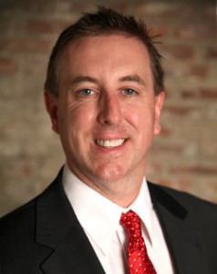 Headshot of Anthony Montagna, III smiling in a suit and red tie!